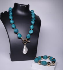 Turquoise nugget necklace with baroque pearl pendant and matching turquoise-gold bracelet displayed on a black jewellery bust and white stand.