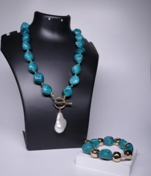 Turquoise nugget necklace with baroque pearl pendant and matching turquoise-gold bracelet displayed on a black jewellery bust and white stand.