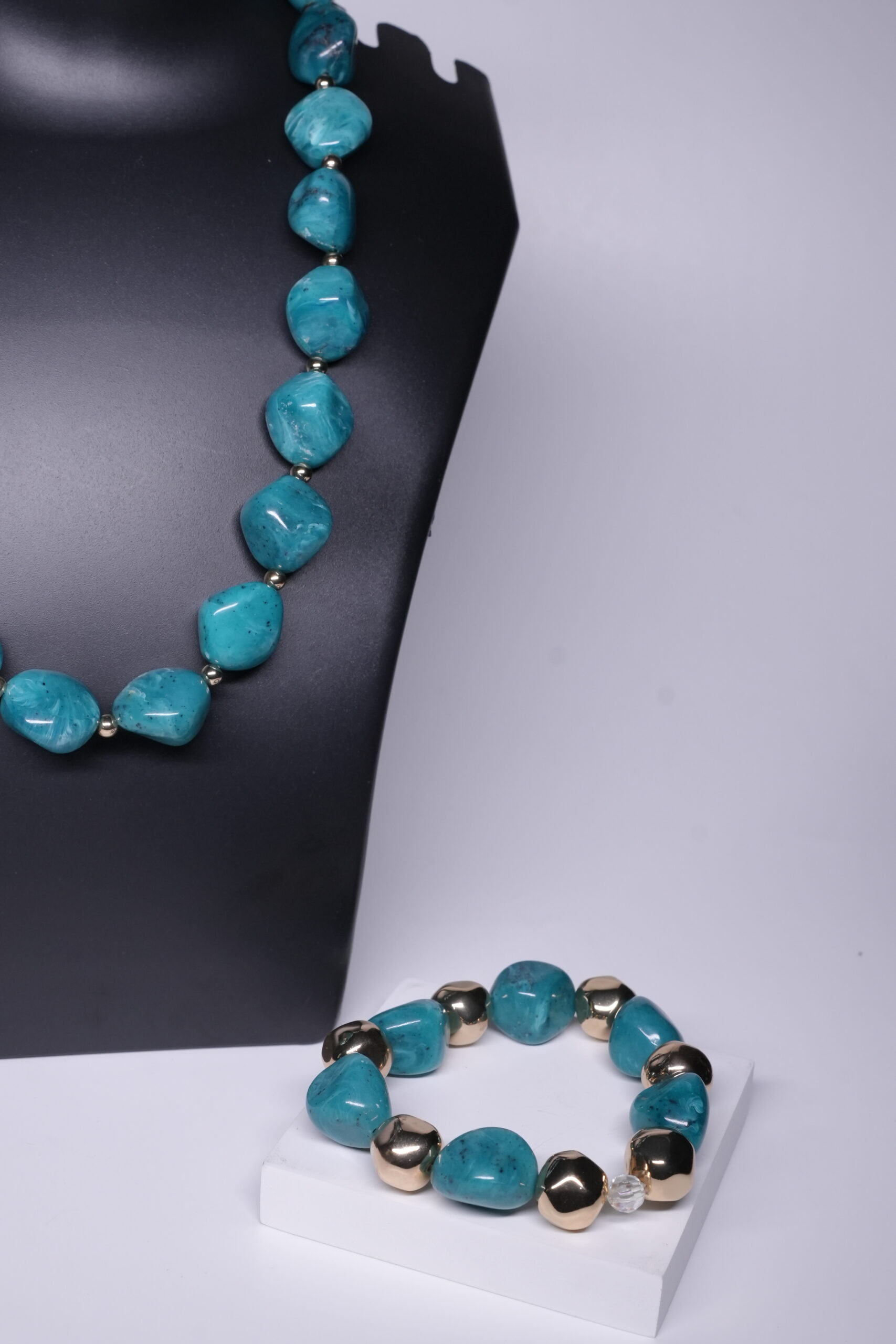 Close-up of turquoise baroque pearl necklace showing toggle clasp, pearl drop, and gold plated bead details.