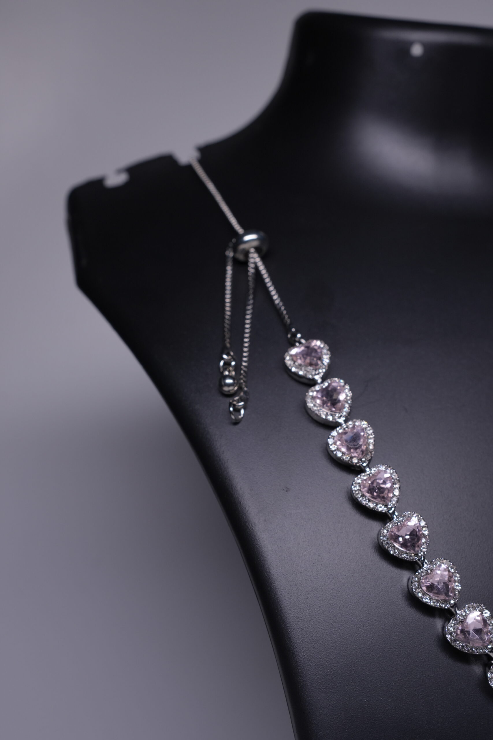 Close-up of pink heart stone necklace showing adjustable slider chain and sparkling stone details.