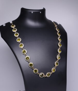 Gold plated necklace with olive green crystal floral clusters and sparkling stone accents, displayed on a black jewellery bust.