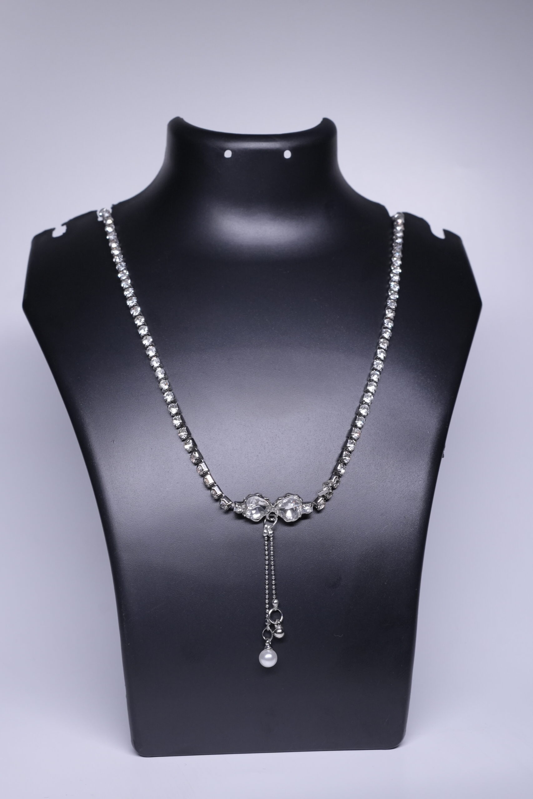 Close-up of CZ tennis necklace showing faceted stones and beaded pearl drop detail.