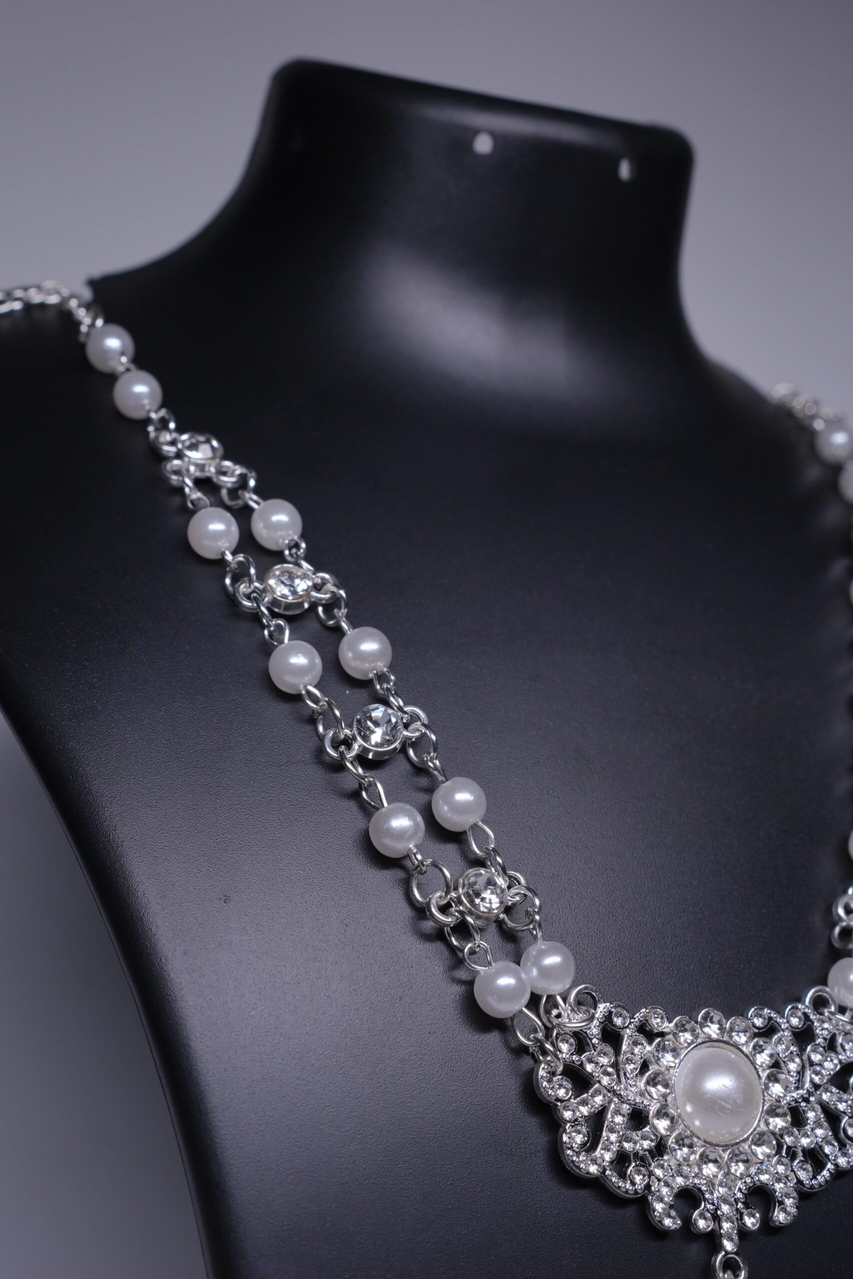 Close-up of bridal statement necklace showing filigree pendant, CZ stones, and pearl drop detail.