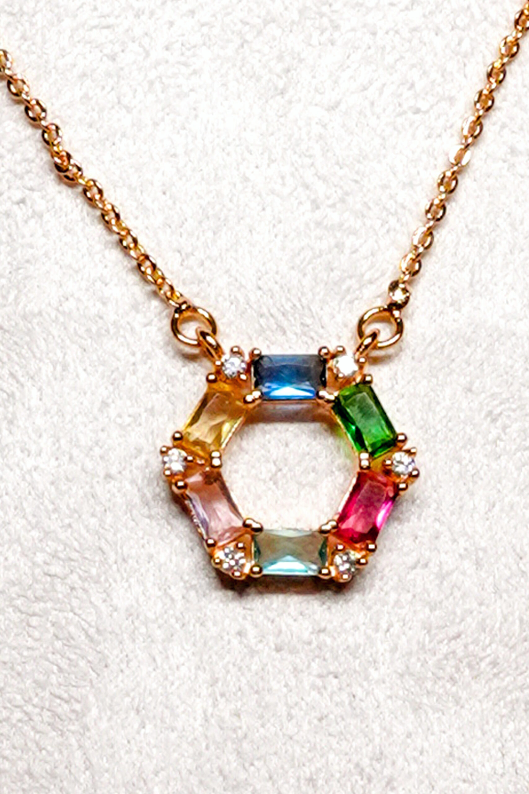 Close-up of the hexagon pendant set with blue, green, pink and aqua baguette zircons