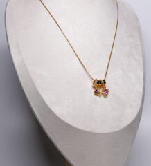 Gold plated snake chain necklace from d2dazzle with pink and lilac zircon heart charms and a gold star charm on sparkling rings, shown on a grey bust stand.