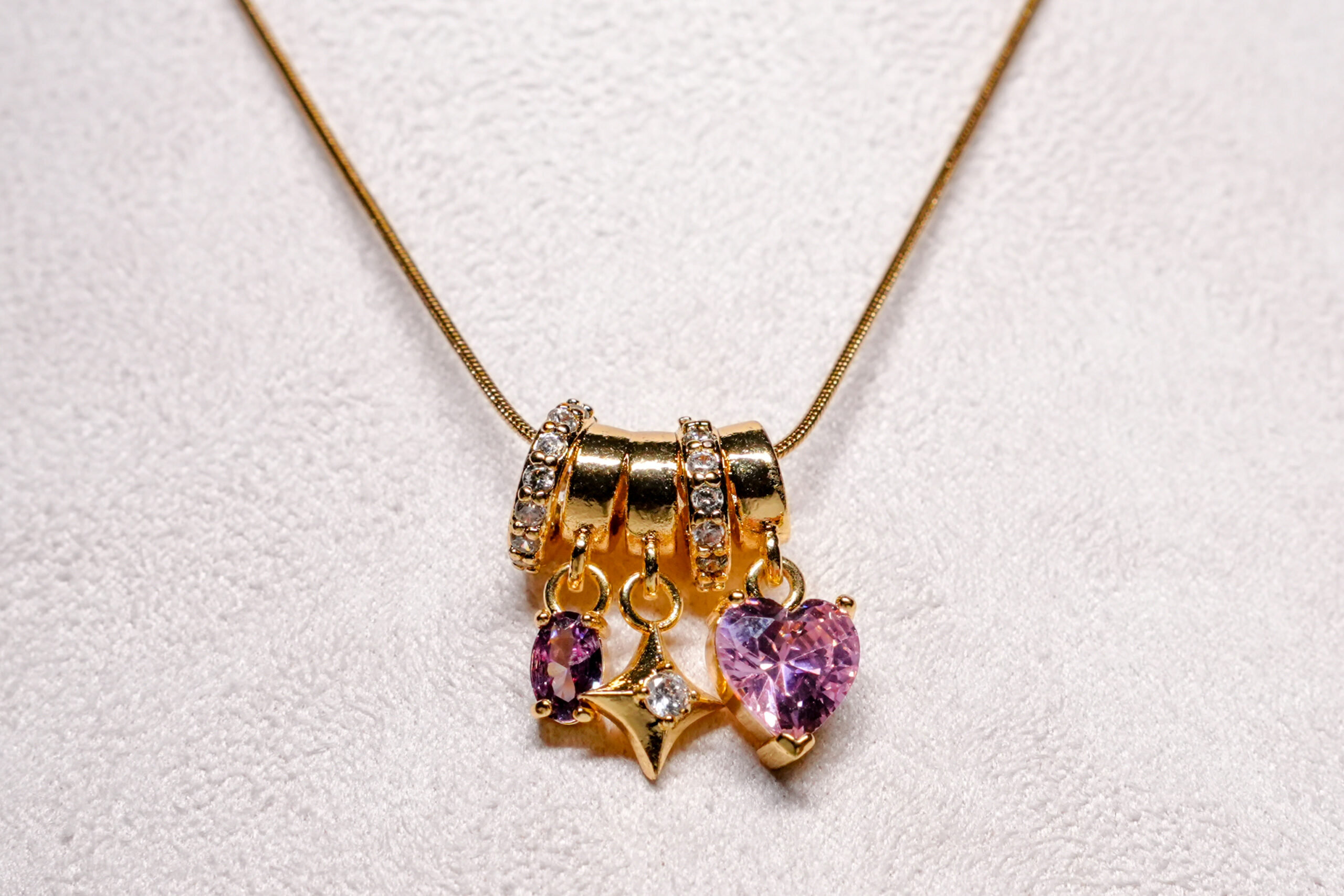 Close-up of pink zircon heart and gold star charms on a D2Dazzle necklace