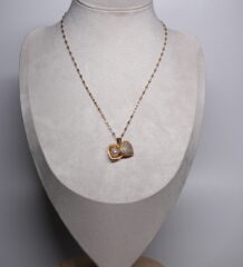 Gold plated heart pendant necklace from d2dazzle with a sparkling pavé zircon heart and an open heart holding a white pearl, on a fine gold sparkle chain displayed on a grey bust stand.